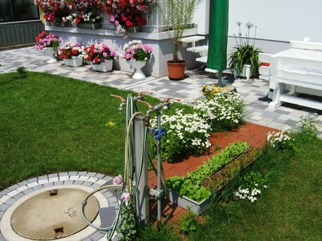 Regenwasserzisterne mit Regenwasserzapfstelle im Vorgarten Regenwassersammelbehälter mit Regenwasserversorgung im Hausgarten